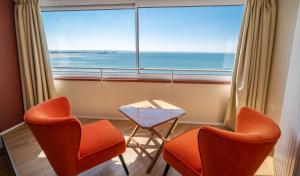 a room with two chairs and a table and a large window at LOGIS HOTEL - La Petite Rade in Le Havre