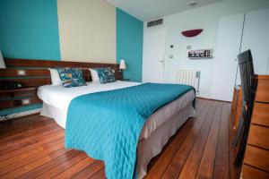 a bedroom with a bed with blue walls and wooden floors at LOGIS HOTEL - La Petite Rade in Le Havre