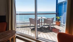 a balcony with a table and chairs and the ocean at LOGIS HOTEL - La Petite Rade in Le Havre