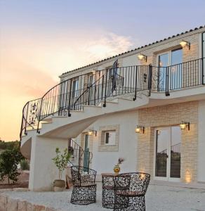 a house with a staircase and two chairs in front of it at Carrua in Marzamemi