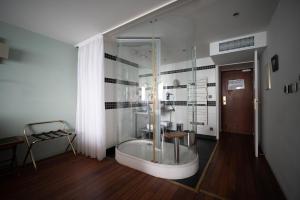 a bathroom with a glass shower and a tub at LOGIS HOTEL - La Petite Rade in Le Havre