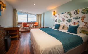 a hotel room with a large bed and a desk at LOGIS HOTEL - La Petite Rade in Le Havre