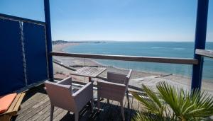 a balcony with chairs and a table and a beach at LOGIS HOTEL - La Petite Rade in Le Havre