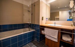 a bathroom with a tub and a sink and a bath tub at LOGIS HOTEL - La Petite Rade in Le Havre