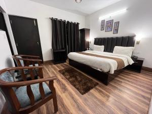 a bedroom with a large bed and a chair at Cedar Woods Resort in Nainital