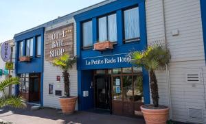 a blue and white building with palm trees in front of it at LOGIS HOTEL - La Petite Rade in Le Havre