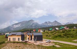 een klein stadje in een veld met bergen op de achtergrond bij Moticki Gaj Cottage in Žabljak