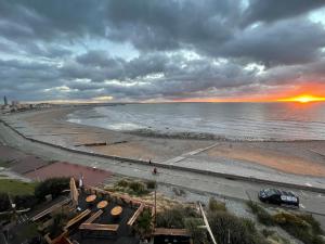a view of a beach at sunset with a cloudy sky at LOGIS HOTEL - La Petite Rade in Le Havre