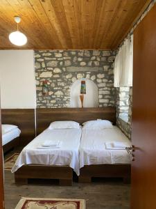 1 dormitorio con 2 camas y techo de madera en Aria Baci Guest House en Berat