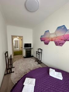 a bedroom with a purple bed and a tv at Emerald Apartament in Chernivtsi