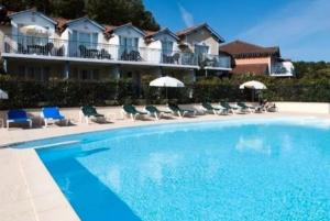 una piscina frente a un hotel con sillas y sombrillas en Location Maison Meublée Marciac, en Marciac