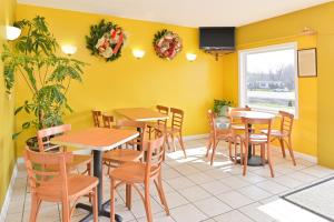 a restaurant with yellow walls and tables and chairs at American Inn Princeton in Princeton