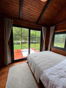 a bedroom with a bed and large windows at Noveli Tiny House in Ardeşen