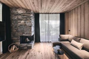 sala de estar con sofá y chimenea de piedra en Waldchalet mit Jacuzzi, en Racines