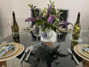 una mesa de cristal con un jarrón de flores púrpuras y botellas de vino en Sleeps 6 near the beach, en Redruth