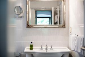 a white bathroom with a sink and a mirror at Schloss Plars wine & suites in Lagundo