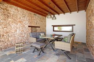 un patio con mesa, sillas y pared de piedra. en Casa Rural Berrenda en Tiscamanita