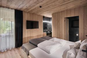 a bedroom with a large white bed and a television at Ruhiges Waldchalet in Racines