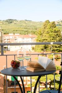 a table with two glasses of wine and a book at Hotel & Apartments Sasso in Diano Marina