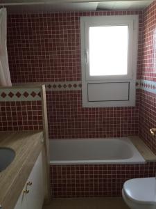 baño de azulejos rojos con bañera y ventana en Brises del Mar 3-3, en L'Estartit