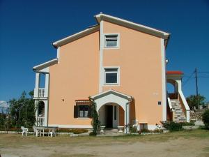 a large pink house with two chairs in front of it at Apartments Lidija in Lopar