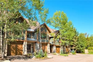 una casa de madera con garaje y árboles en Équinoxe 164-2 / Exclusive Mountain Home With View, en Mont-Tremblant