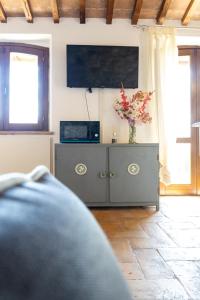 una sala de estar con TV y un armario con un jarrón de flores en Rustic House, con patio e giardino, Assisi centro, en Asís