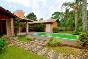 un patio trasero con piscina y una casa en Pousada ESQUINA DO ATLANTICO SUL, en Tubarão