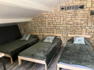 two beds in a room with a brick wall at Charmant petit dortoir 3 places in Chazelles