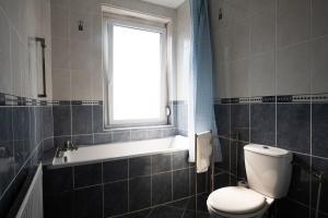 een badkamer met een toilet, een bad en een raam bij Maison cosy 4 chambres, terrasse, garage privé in Croix