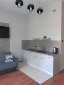 a kitchen with white cabinets and a blue couch at APARTAMENT KOSZARY na NOVO in Mrągowo