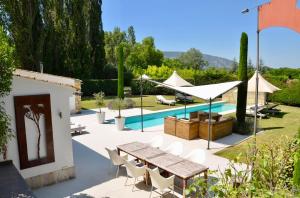 a patio with a table and chairs and a pool at Les Cerisiers maison bertuli climatisé, Piscine chauffée, lit King size, classé 5 étoiles in Oppède