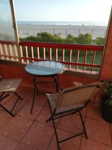 Una mesa y sillas en un balcón con vista al mar. en Condominio Ilimay Las Cruces, en Las Cruces