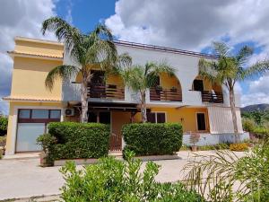 een geel gebouw met palmbomen ervoor bij villa xenia in Avola