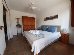 a bedroom with a large white bed with blue pillows at Casa Amani in Viñuela
