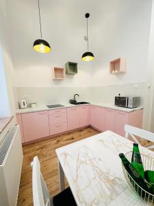 kuchnia z różowymi szafkami i stołem w obiekcie Apartamenty Kamienica Gwiazda w mieście Krynica Zdrój