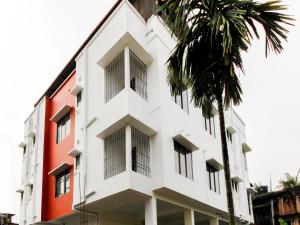 um edifício branco com janelas com barras ao lado de uma palmeira em Aditya Guest House em Dispur