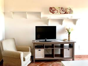een woonkamer met een tv en een stoel bij Casa Vacanza Serena in SantʼAnna Arresi