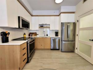 una cocina con armarios blancos y electrodomésticos de acero inoxidable en EDM 1500-2/Your Mountain Oasis en Mont-Tremblant
