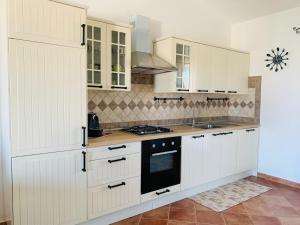een keuken met witte kasten en een fornuis met oven bij Casa Vacanza Serena in SantʼAnna Arresi