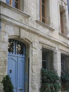 un edificio de piedra con una puerta y ventanas azules en Le Limas en Aviñón