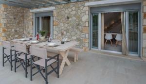 a table and chairs on a patio with a stone wall at Villa Martha Perithia Corfu in Perítheia