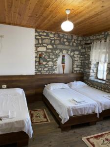 Un dormitorio con dos camas y una pared de piedra. en Aria Baci Guest House, en Berat