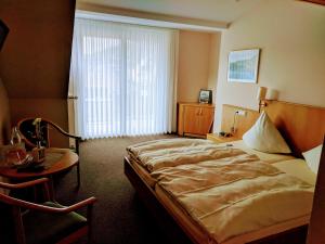 ein Hotelzimmer mit einem großen Bett und einem Tisch in der Unterkunft Weinhaus Berg in Bremm