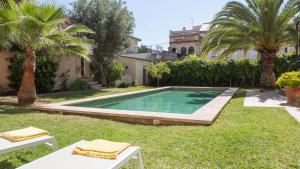 a swimming pool in the yard of a house with palm trees at Villa Palma 3 in Palma de Mallorca