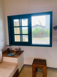 a room with a window and a bench and a table at Vila Aratu Corumbau in Corumbau