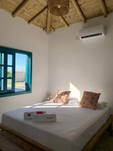 um quarto com uma grande cama branca e uma janela em Vila Aratu Corumbau em Corumbau