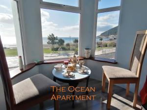 een appartement aan de oceaan met een tafel en stoelen en uitzicht op de oceaan bij Mourne Mountain Art Apartments in Newcastle