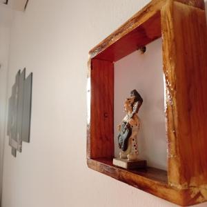 een houten spiegel met een beeldje op een plank bij Pousada do Rock in Arraial d'Ajuda