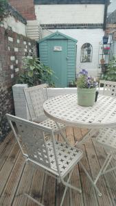 un tavolo e sedie su un patio con un vaso di fiori di Martha's cottage by the sea a Gorleston-on-Sea